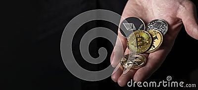 Bitcoin and other different cryptocurrency coins in male hand palm over black background with copy space for text Editorial Stock Photo
