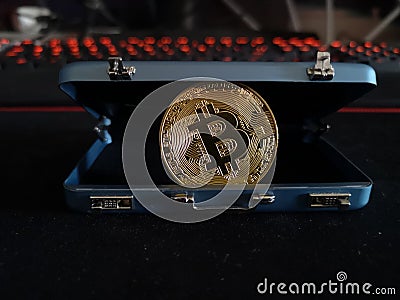 Bitcoin peeping from a suitcase on the background of a glowing keyboard in dark tones Stock Photo