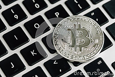 Bitcoin silver coin on computer laptop keyboard. Virtual cryptocurrency concept Stock Photo