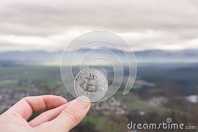 Bitcoin silver coin, Hand hold bitcoin above the city Stock Photo