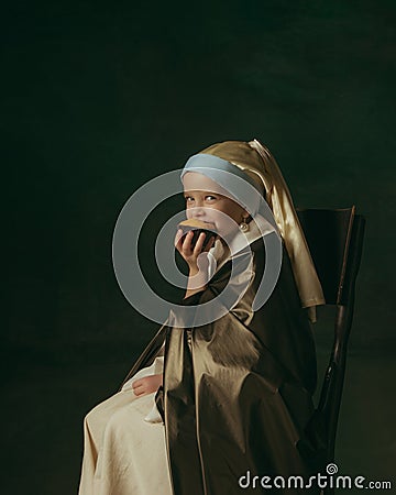 Medieval little girl as a lady with a pearl earring on dark studio background. Concept of comparison of eras, childhood Stock Photo