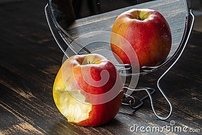 The bitten apple is reflected in the mirror close up Stock Photo