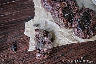 Bitten dark chocolate chip cookies on baking paper over wooden rustic background Stock Photo