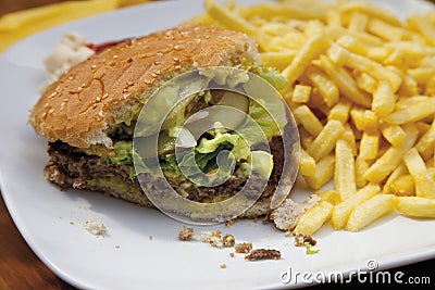 Bitten hamburger with chips in plate Stock Photo