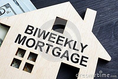 Biweekly mortgage. Wooden model of house and money Stock Photo
