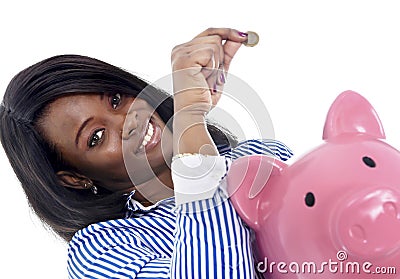 Black African American business woman putting coin into oversized pink piggybank Stock Photo