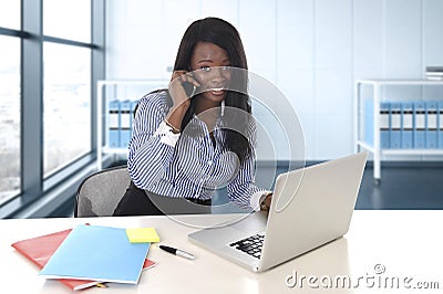 Black African American ethnicity woman working at computer laptop at office desk smiling happy Stock Photo