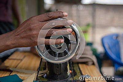 Black African Man hand holding a rotating wheel of the sewing machine in the Village Open Air Editorial Stock Photo