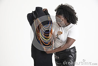 Black African woman working arranging necklaces on a tailors dummy. Stock Photo