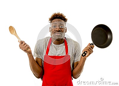 Black afro american man home cook in chef apron cooking pan and spoon lost and overworked Stock Photo