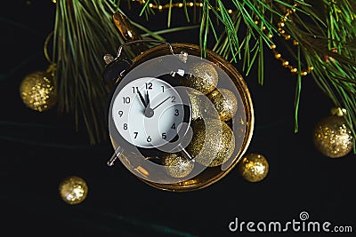 Black Alarm clock and fir tree branch, gold christmas decorations green velours glitte, shine background. Eve Time Concept on tabl Stock Photo