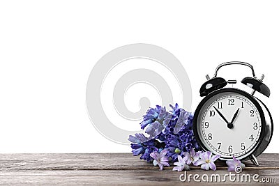 Black alarm clock and spring flowers on table against white background, space for text. Time change Stock Photo