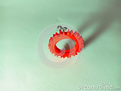 a black ant standing up on red colour mechanical engineering wheel on white background Stock Photo