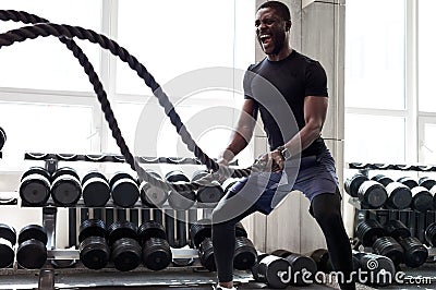 Black athlete doing battle rope exercise at crossfit gym Stock Photo