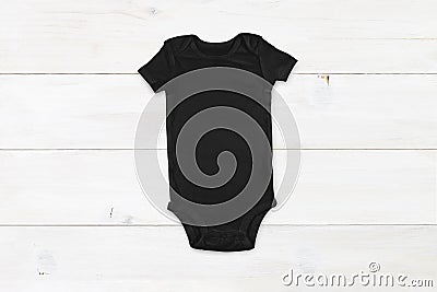 Black baby onesie mockup on white wood background Stock Photo