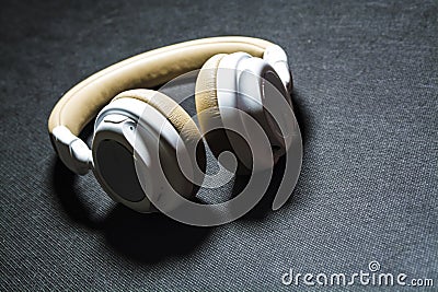 Black background. Big earphones for listening of music. White and beige color. Skin. Modern technologies. Portable equipment. Stock Photo