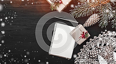 On a black background, a fir tree with cone and decorative objects. Gift and a note book or a Christmas message. Stock Photo