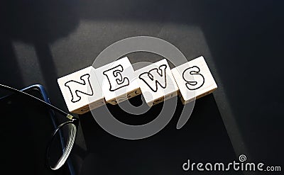 On a black background on white cubes, the inscription - news, next to black-rimmed glasses and a phone. Stock Photo