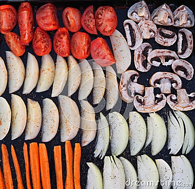 Black baking tray from a home oven with sliced vegetables for baking or drying.Homemade cooking with chips and baked vegetables. Stock Photo