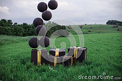 Black balloons and big black boxes in the landscape. Stock Photo