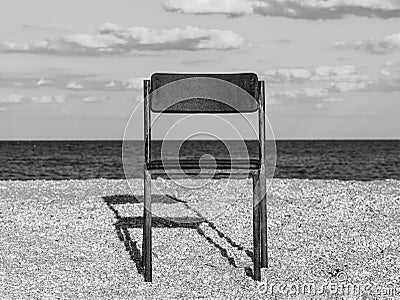 Black beach chair on empty sand beach with blue sea water background Minimalism style autumn travel relaxation No people Stock Photo