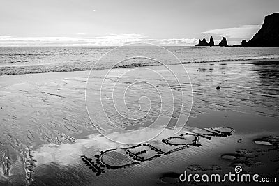 Black beach in Iceland, basalt cliffs in the ocean and iceland text in the sand. Stock Photo