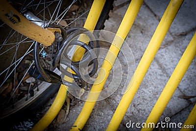 Black bicycle safety locker and wheel on a yellow pole of a bike parking Stock Photo