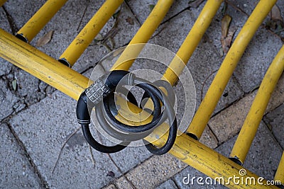 Black bicycle safety locker on a yellow pole of a bike parking Stock Photo