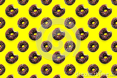 Black bited donuts with red glaze on yellow background seamless pattern top view. Food dessert flatly flat lay of Stock Photo