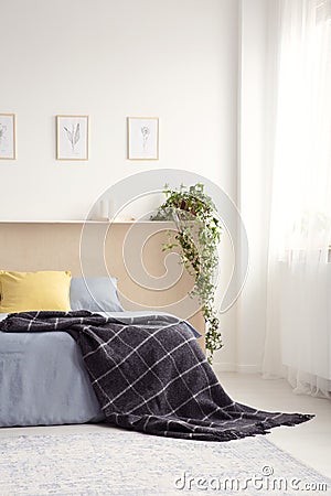 Black blanket thrown on bed in real photo of white bedroom inter Stock Photo