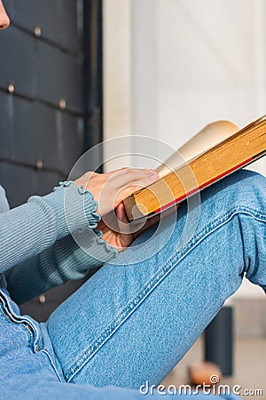 Black book with yellow pages in the hands of a person with blue t-shirt Stock Photo