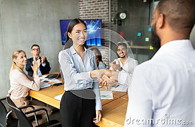 Black Boss Shaking Hands And Congratulating Asian Female Employee With Business Success Stock Photo