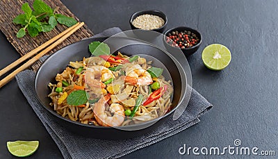 In a black bowl, noodles, veggies, and prawns are stir-fried. slate background. higher perspective Stock Photo