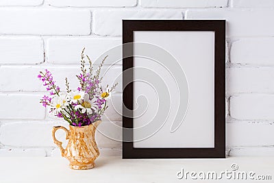 Black brown frame mockup with chamomile and purple flowers in g Stock Photo