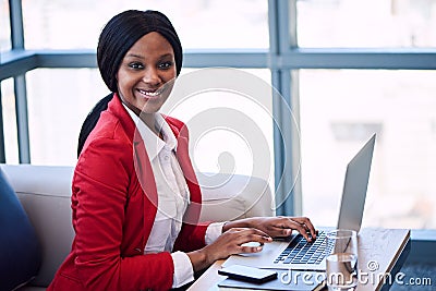 Black businesswoman smiling at the camera while seated on sofa Stock Photo