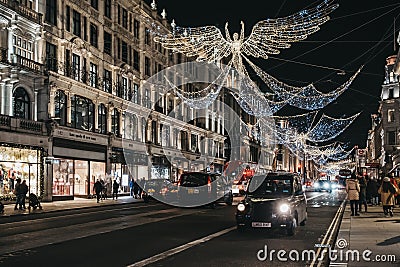 Black cab under angel Christmas lights on Regent Street, London, UK, in the evening, motion blur Editorial Stock Photo