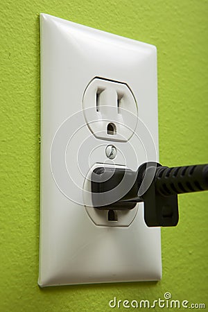 Black cable plugged in a white electric outlet Stock Photo