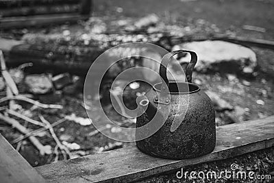 Black camping kettle stands on benches in the forest Stock Photo