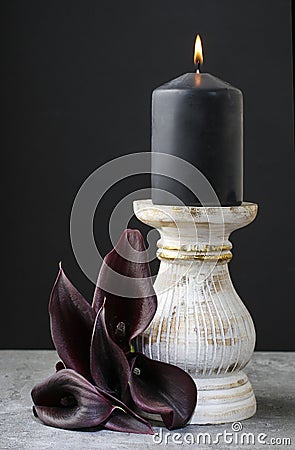 Black candle and black calla flowers (Zantedeschia). Stock Photo