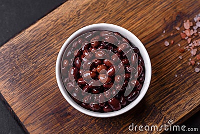 Black, canned beans in a white saucer against a dark concrete background Stock Photo