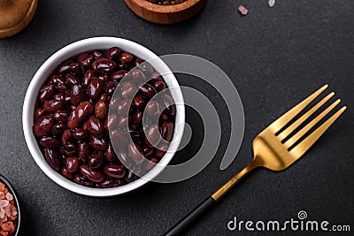 Black, canned beans in a white saucer against a dark concrete background Stock Photo
