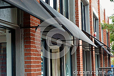 Black canvas awnings projecting out from a brick wall. Stock Photo