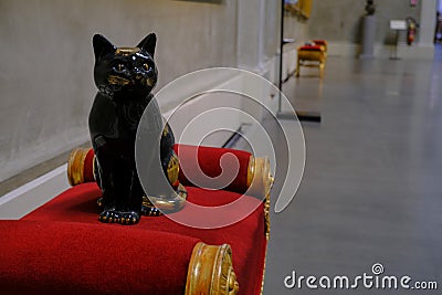 Black cat sculpture sitting on red velvet chair in National Gallery, Galleria Nazionale of Palazzo Pilotta Editorial Stock Photo