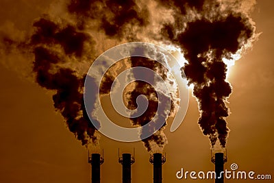 Black caustic poisonous smoke curls out of the pipes in the sunset sky. Toxic fumes chimney piping smoke or steam poisoned air, Stock Photo