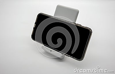 Black cellphone charging on modern designed wireless charger sta Stock Photo