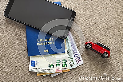 Black cellphone, money euro banknotes bills, passport and toy car on copy space background. Travel light, comfortable journey Stock Photo