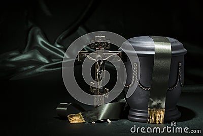 Black cemetery urn with Orthodox cross dark green ribbon, on deep green background Stock Photo