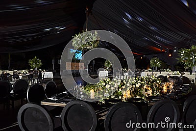 Black chairs with green floral centerpiece at night luxury romantic indoor wedding Stock Photo