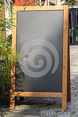 Black chalkboard stand on wood for a restaurant menu in the street Stock Photo