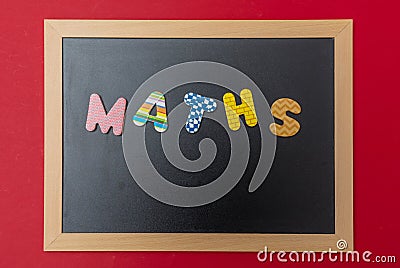 Black chalkboard with wooden frame, word, text maths in colorful letters, red wall background Stock Photo